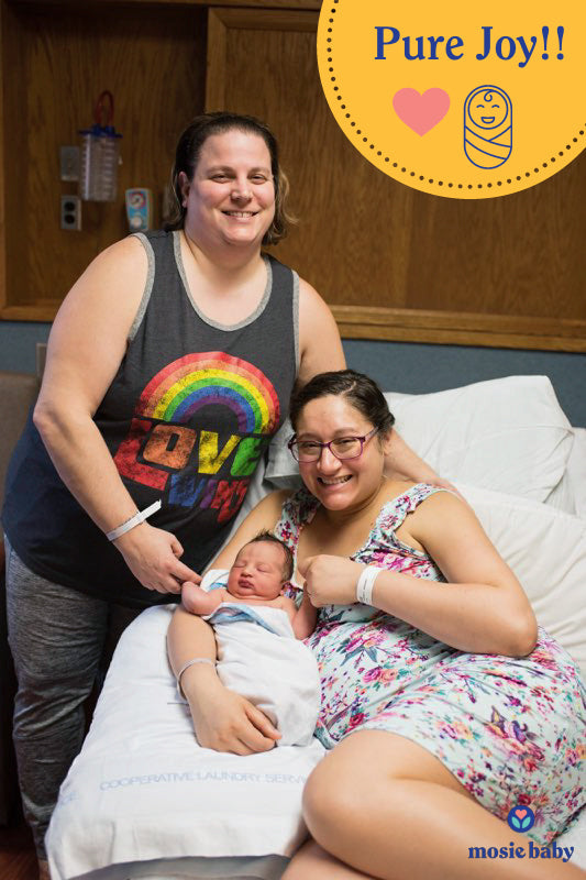 Newborn mosie baby held by his two lesbian mothers