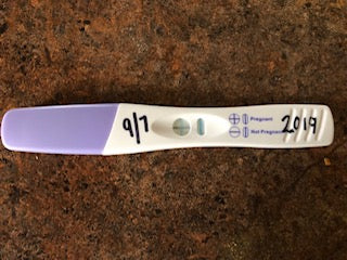 Positive pregnancy test with date written in sharpie on top.