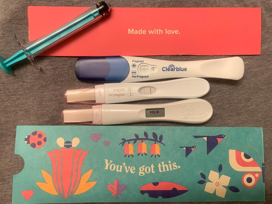 Mosie Baby instructions with Mosie syringe, and three positive pregnancy tests.