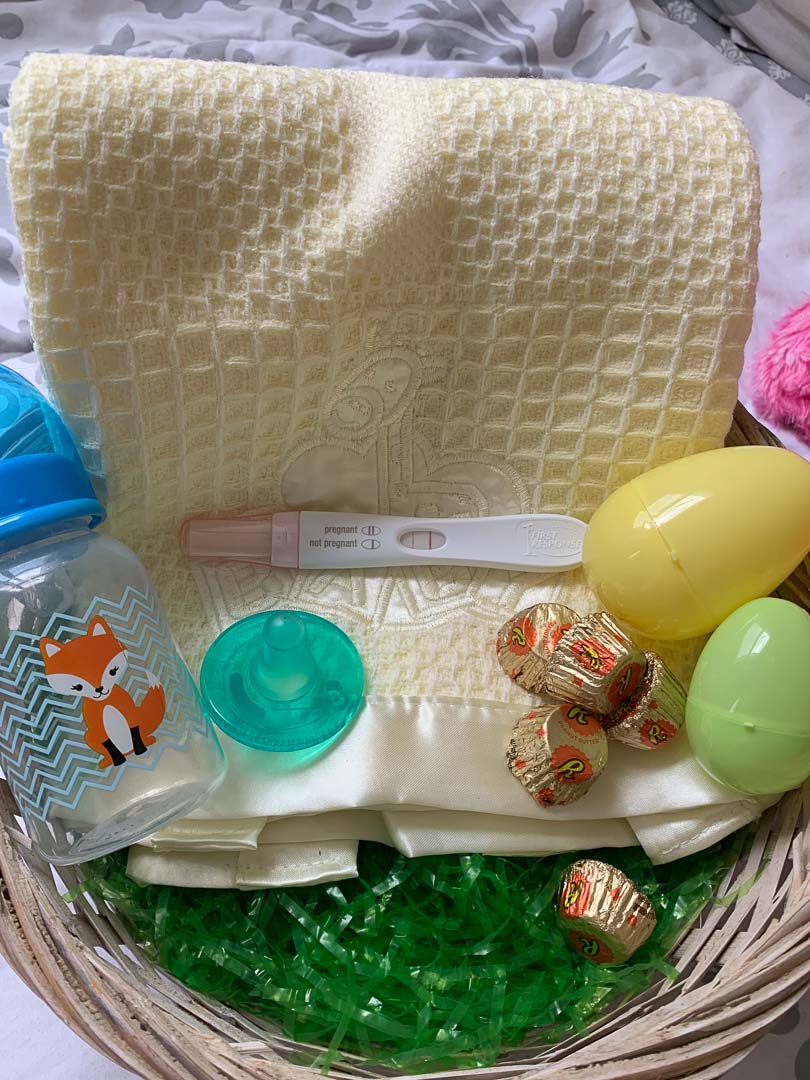 Easter basket with baby bottle, baby blanket and positive pregnancy test