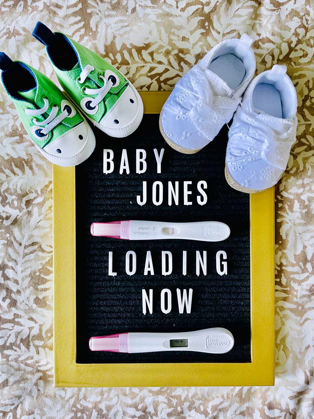 image of a message board that says "Baby Jones loading now" with pregnancy tests and baby shoes on top.