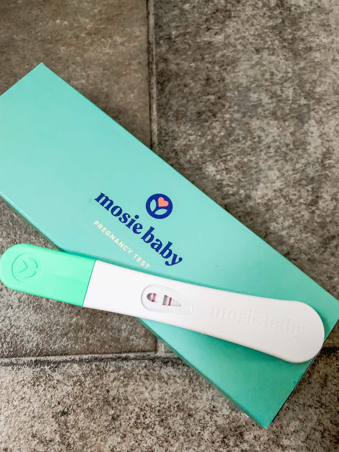 Mosie Baby positive pregnancy test stick on top of Mosie Baby pregnancy box,