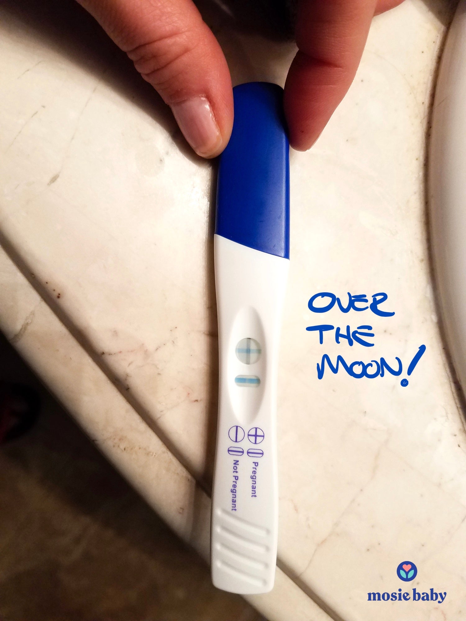 positive pregnancy test held by a Mosie user with the words over the moon
