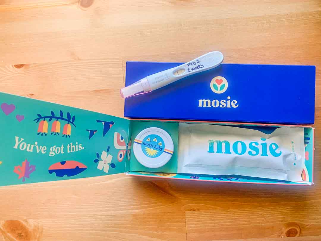 Positive pregnancy test sitting on top of The Mosie Kit!