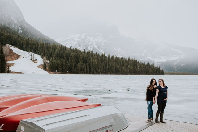 Lesbian couple holding hands on a boat dock in the mountains