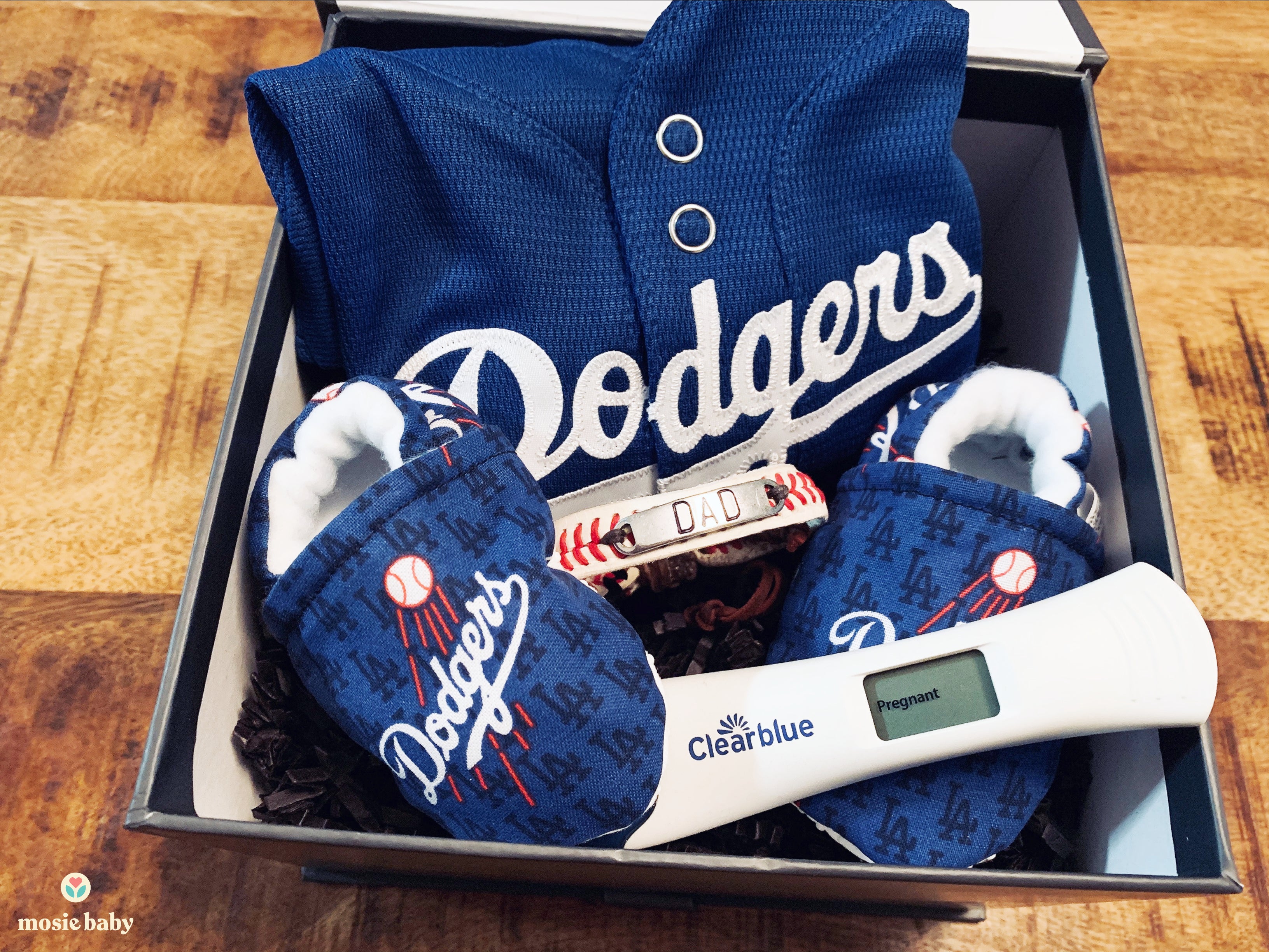 positive pregnancy test inside of a dodgers themed announcement gift box for dad