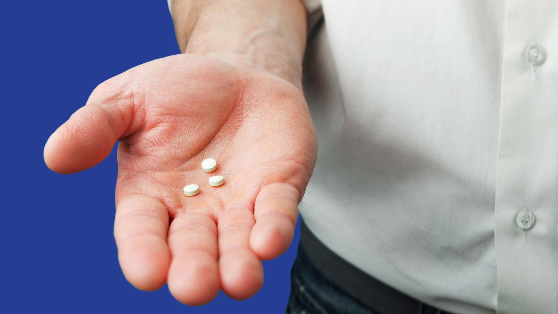 Mosie Baby article image, Clomid for men 101: uses, side effects, and dosage. Image of man holding three white pills