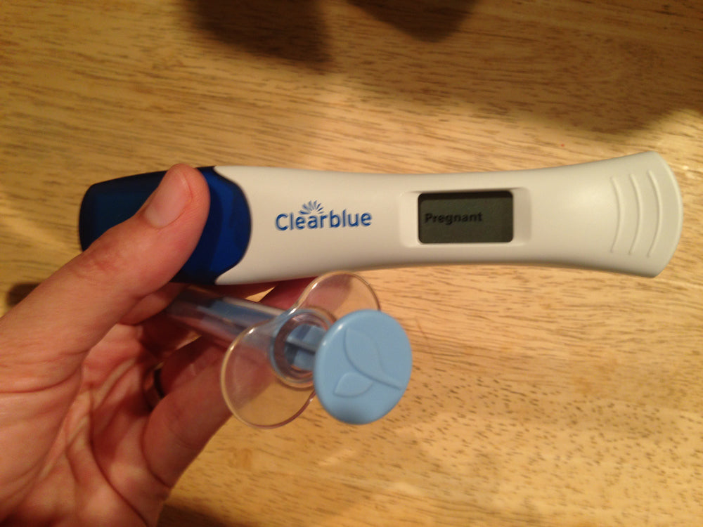 Positive pregnancy test and mosie syringe help by a mosie user